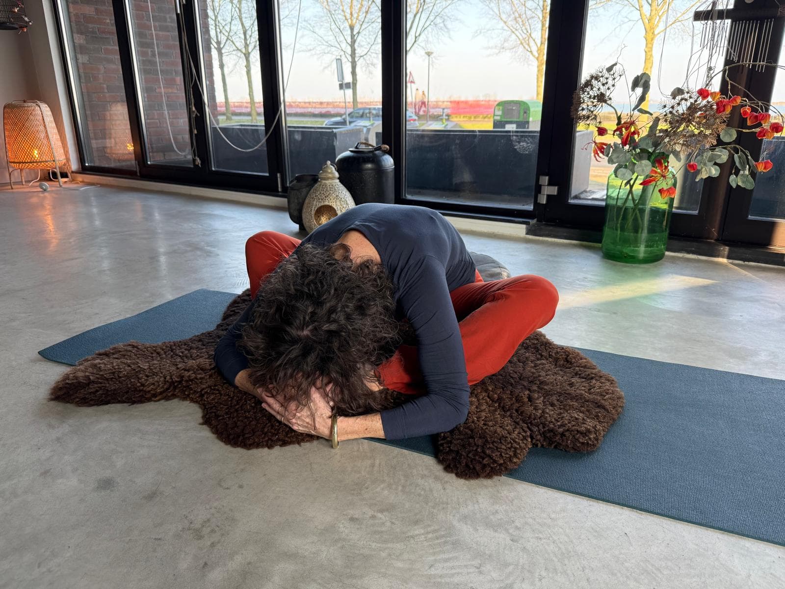 Vrouw in kindhouding op een mat voor een raam met uitzicht op het water bij laag nazomerlicht