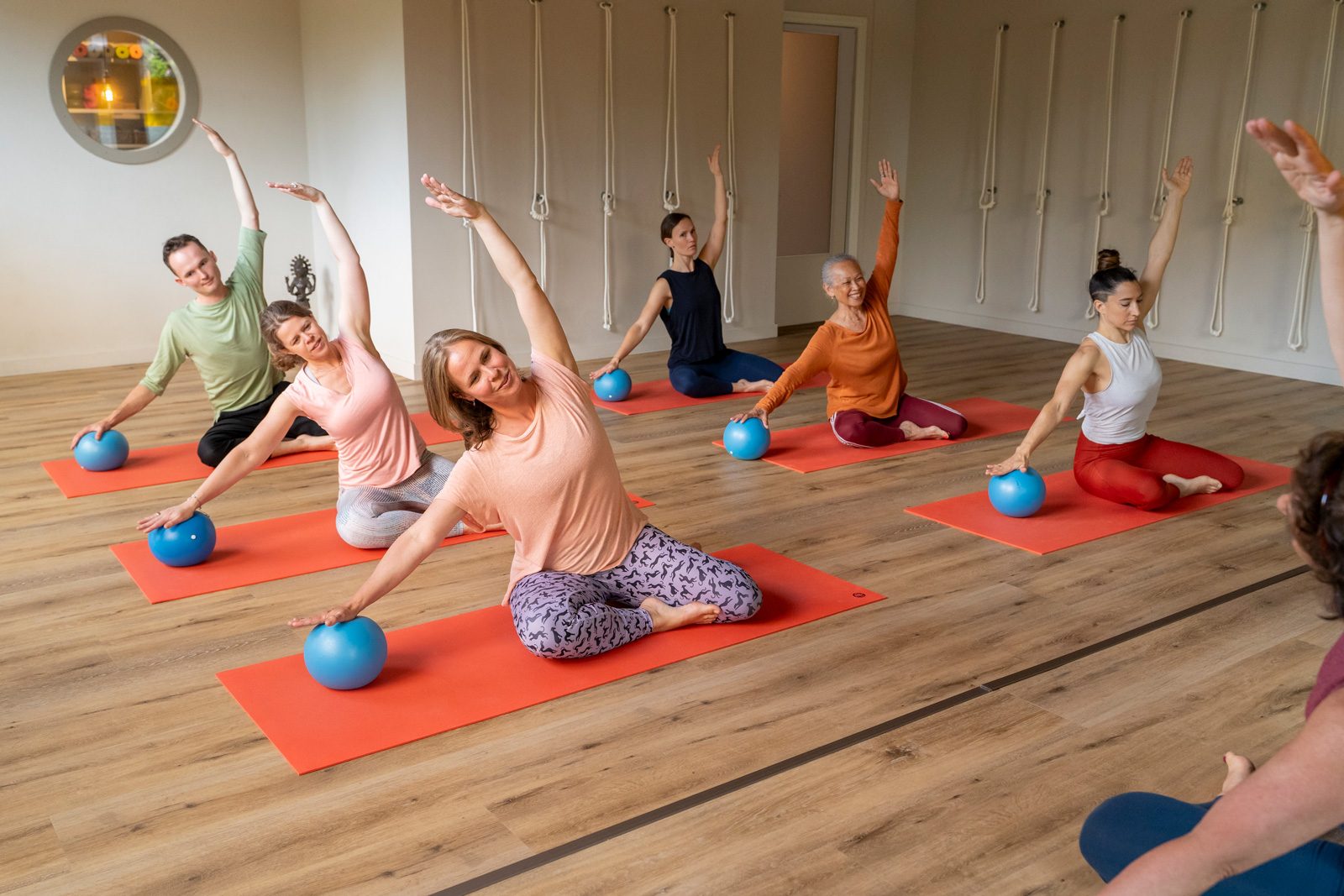Pilates-les met kleine ballen op oranje matten